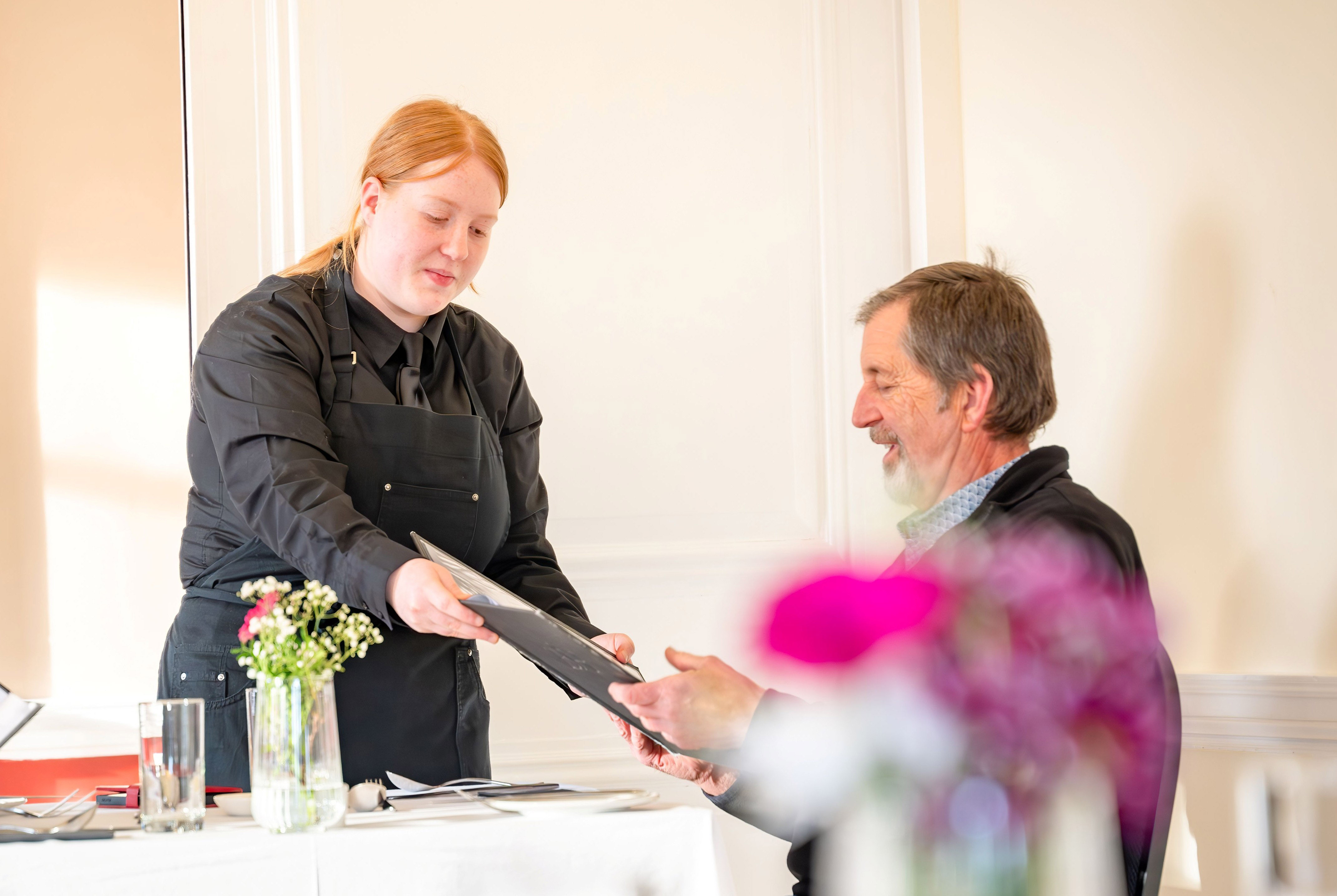 hospitality student passing a menu to a customer hospitality student passing a menu to a customer